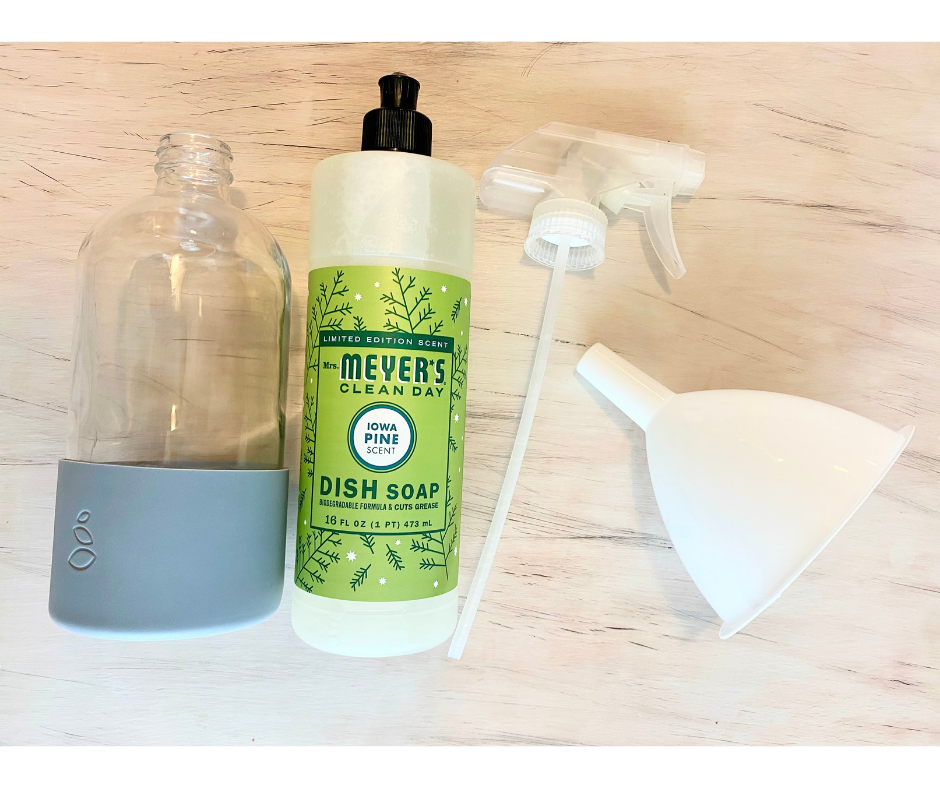 glass spray bottle, Iowa pine scented dish soap, a spray nozzle, and a funnel laying on a distressed wood table