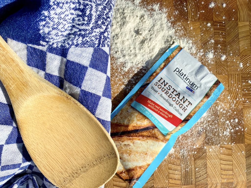 platinum instant sourdough yeast packet on cutting board with wooden spoon and towel
